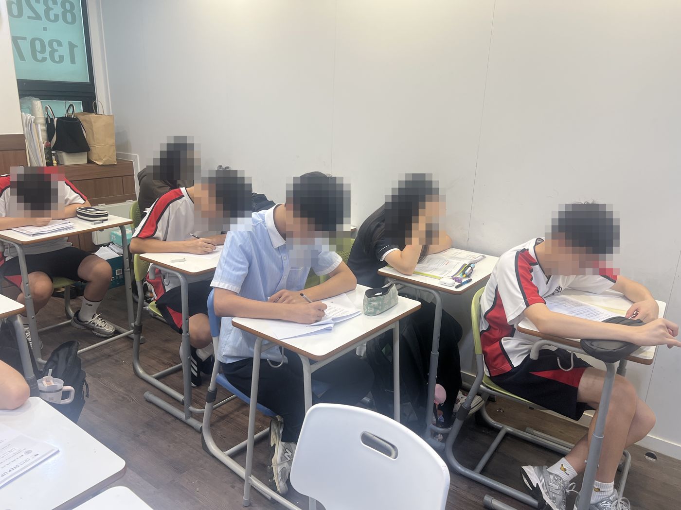 학생들이 책상에 앉아 시험지에 답을 쓰고 있는 장면